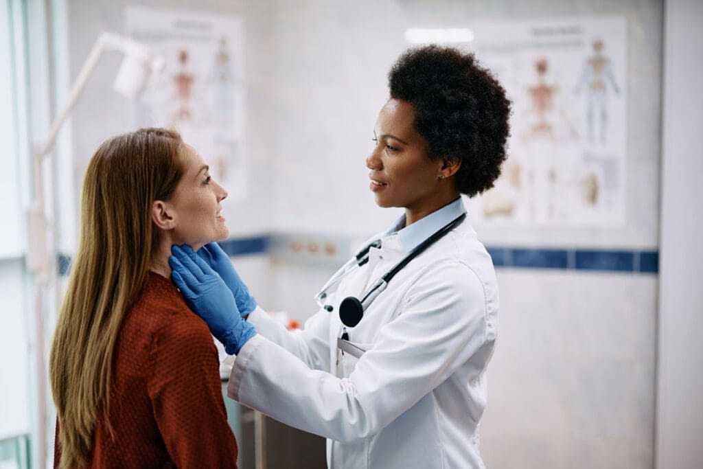 An endocrinologist examines a patient’s thyroid in-office