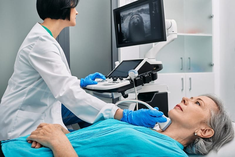 An older patient receives an ultrasound of the thyroid gland.