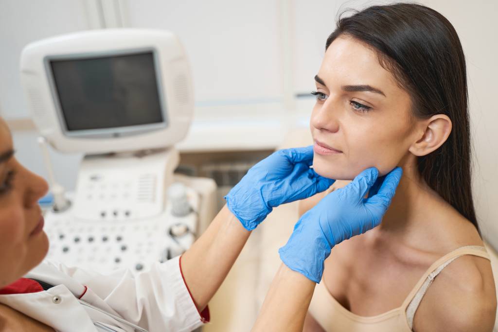A clinician palpates a patient's thyroid before an ultrasound exam.