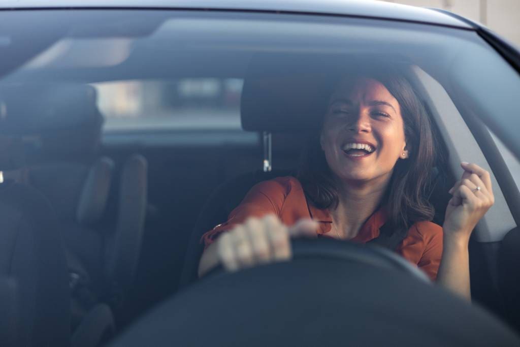 A cheerful woman sings while driving her car a few days following her RFA procedure.