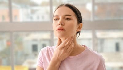 Woman holding her neck area, near nodules